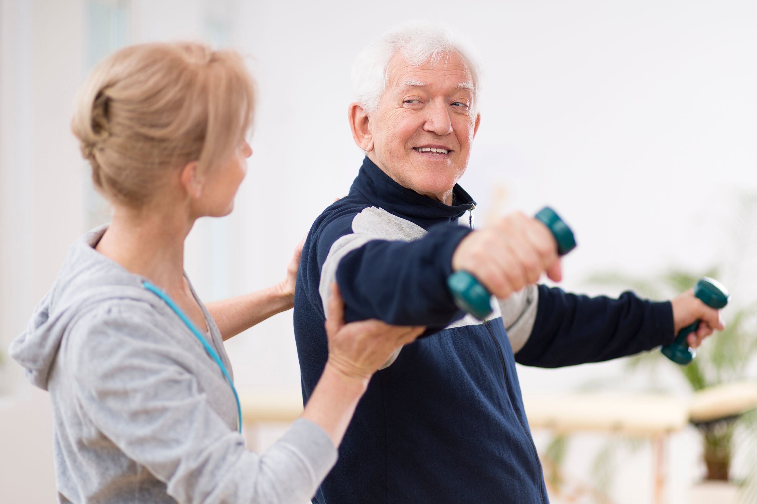 Senior man after stroke at nursing home exercising with professional physiotherapist.