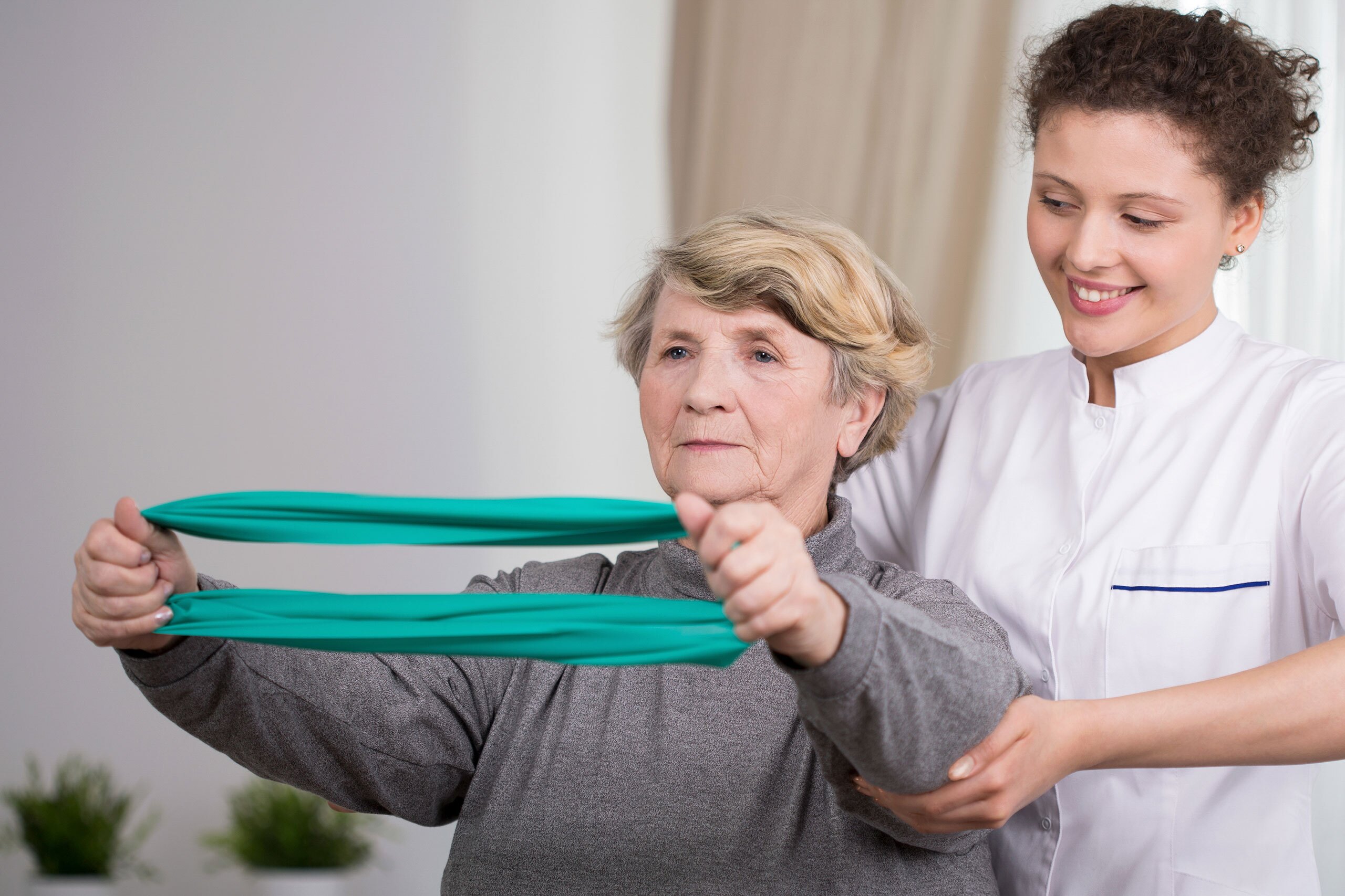 Elderly active woman exercising with young physiotherapist.