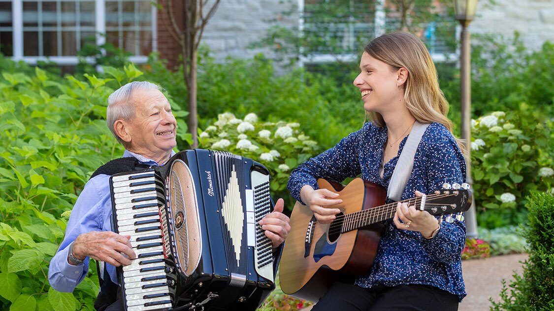McKnight Place resident playing an accordion with a woman playing a guitar.