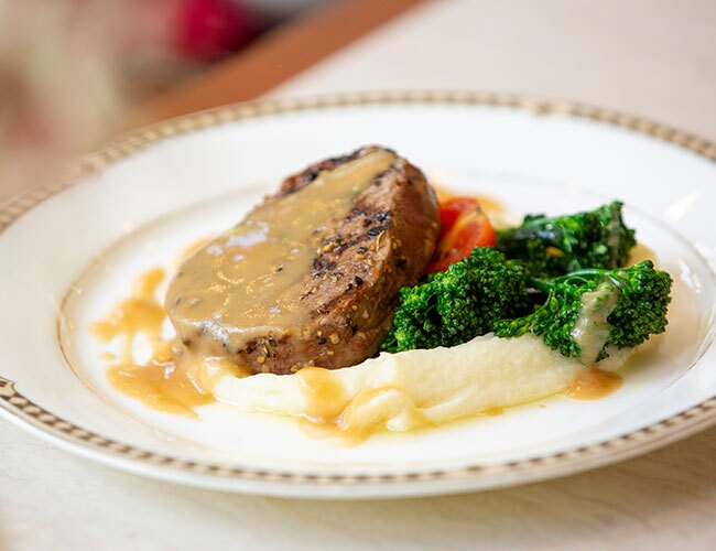 A plate of steak and broccoli on top of mashed potatoes.