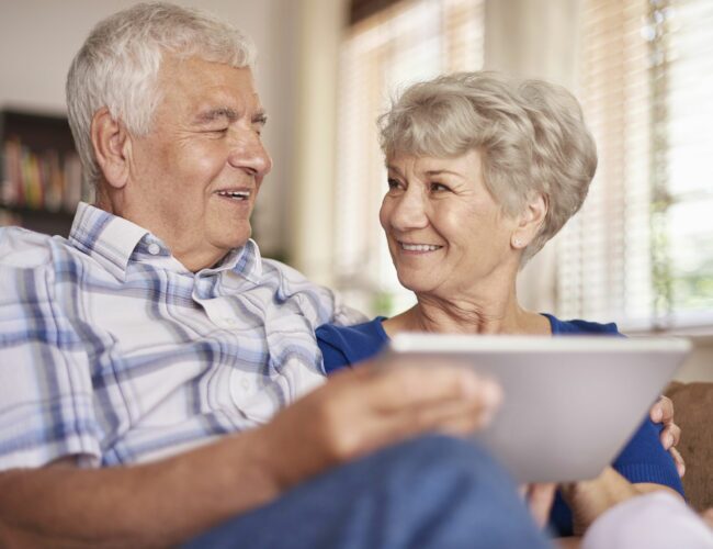 Elderly couple discussing something on an ipad.