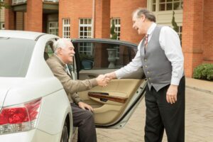 Doorman helping resident out of car.