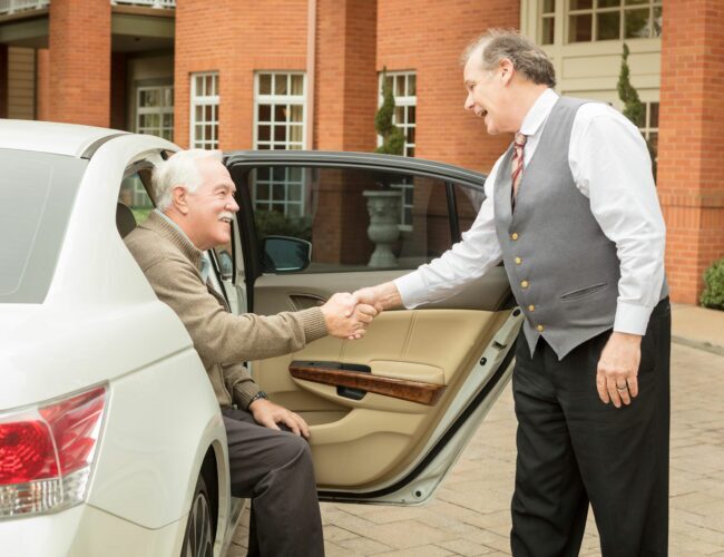 Doorman helping resident out of car.