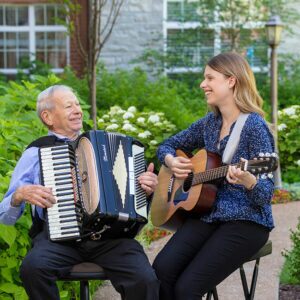 McKnight Place resident playing an accordion with a woman playing a guitar.