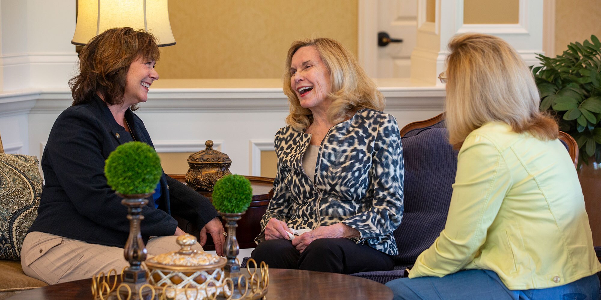 Three ladies sitting and laughing and talking.
