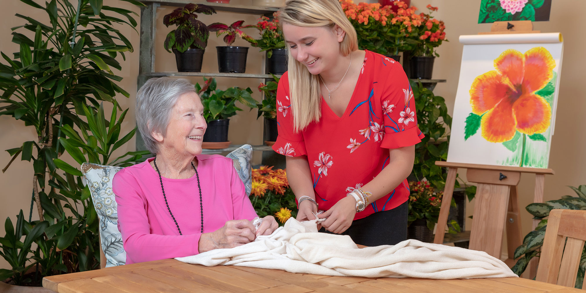 2 women working with a quilt and smiling
