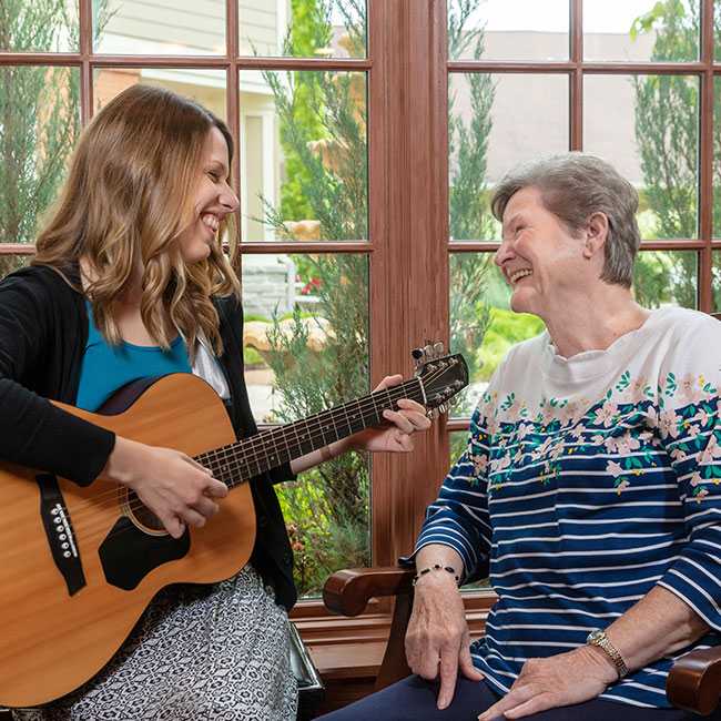 McKnight Place resident listening to woman play the guitar.