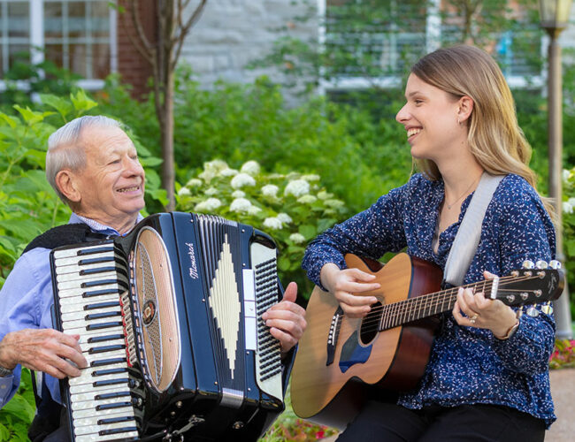 McKnight Place resident playing an accordion with a woman playing a guitar.