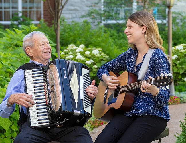 McKnight Place resident playing an accordion with a woman playing a guitar.