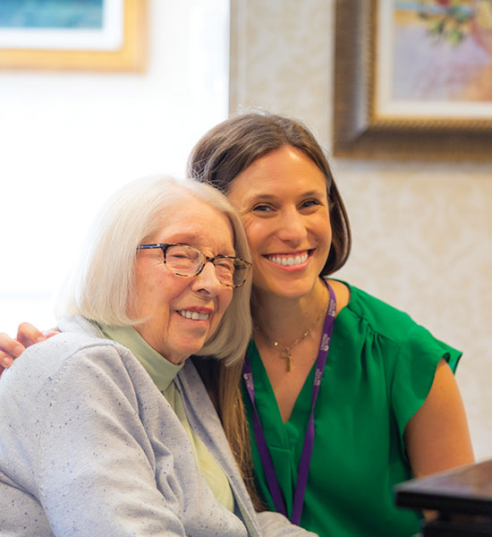 A resident and staff member seated and smiling.