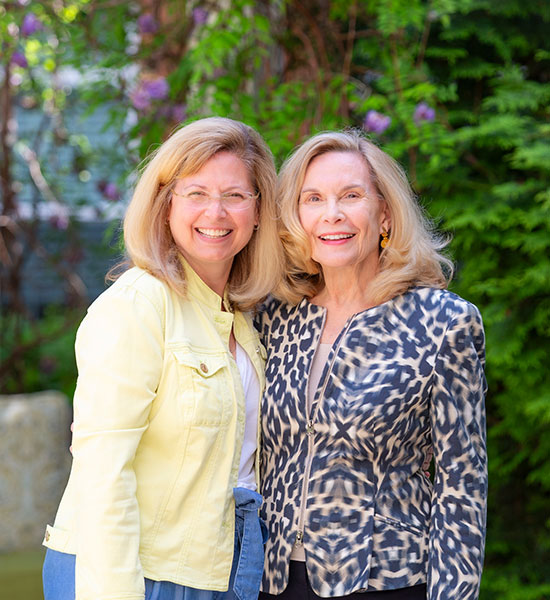 Two ladies smiling outdoors.