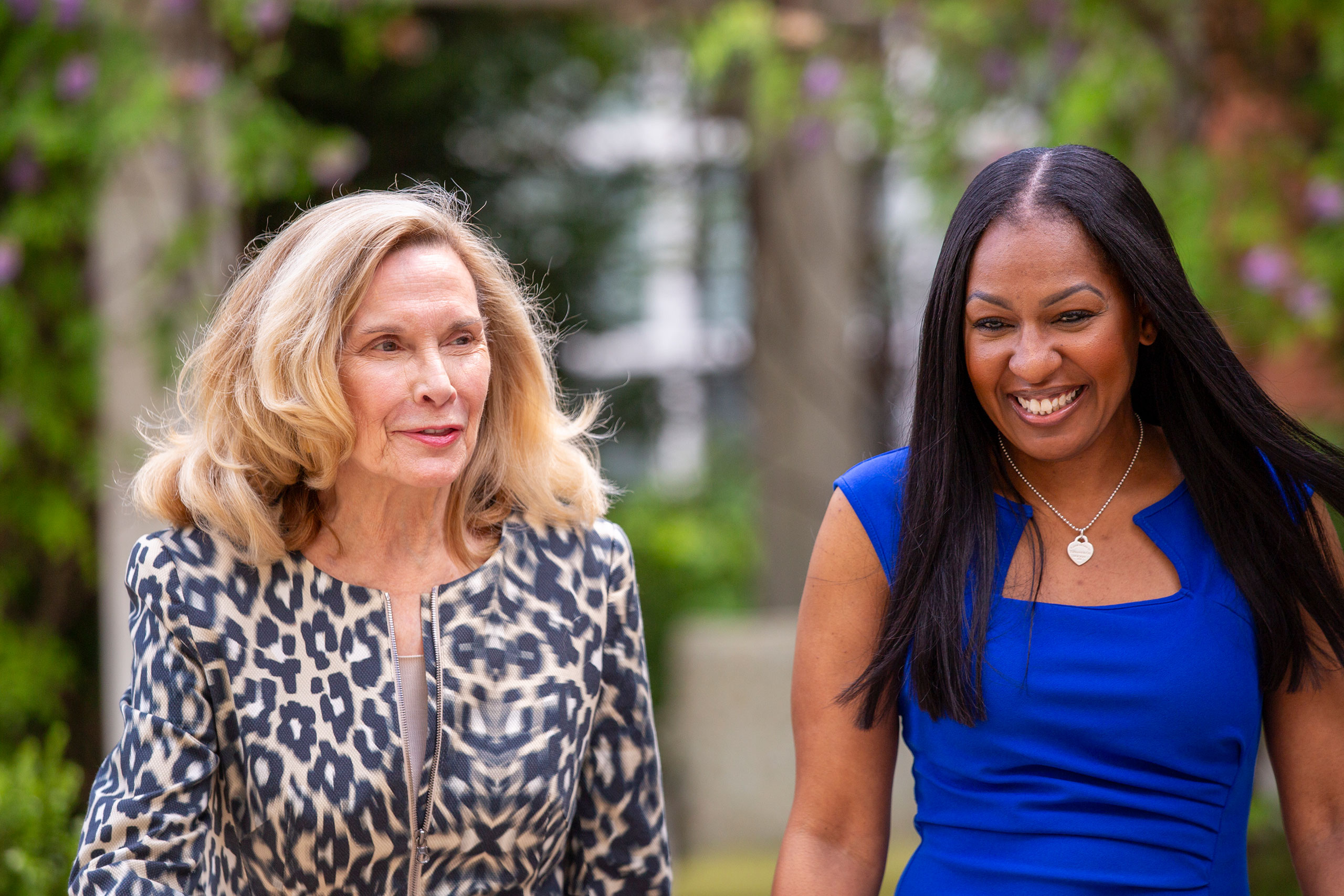 Two ladies walking outdoors in conversation.