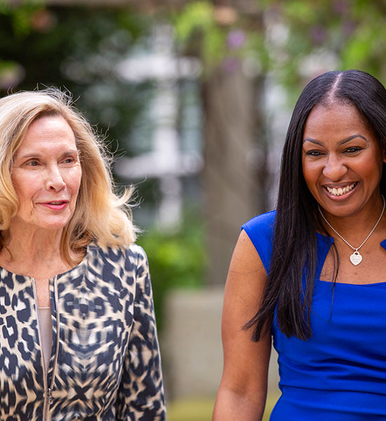 Two ladies walking outdoors in conversation.